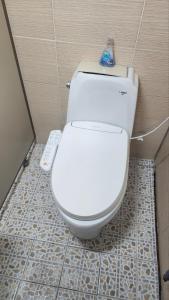 a white toilet in a bathroom with a remote control at Time Stay in Busan
