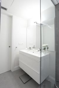 a white bathroom with a sink and a mirror at Apartaments Plaça Del Vi in Girona