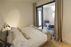 Cama blanca en habitación con ventana en Apartaments Plaça Del Vi en Girona
