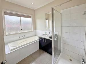 un baño con bañera y lavabo en Spacious 4-Bedroom Family Home | Quiet & Connected, en Truganina