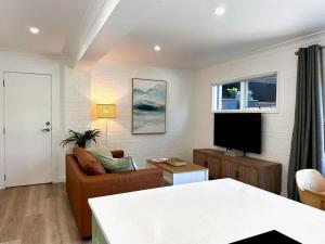 a living room with a couch and a flat screen tv at Elanora Escape- Hillside Retreat in Warriewood