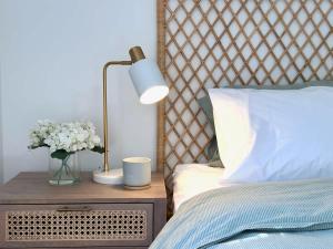 a bed with a lamp and a vase of flowers on a night stand at Elanora Escape- Hillside Retreat in Warriewood +13 photos
