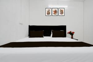 a bedroom with a white bed with two pictures on the wall at Super Hotel O Gaya Railway Junction Formerly Family Guest House in Gaya