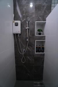 a shower in a bathroom with a black tile wall at บ้านผูกรัก ทะเลหมอก ณ เขาค้อ in Khao Kho