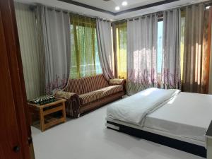 a bedroom with a bed and a couch and windows at Pacific Guest House Skardu in Skardu