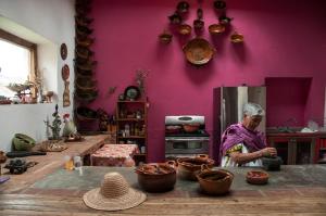 Uma mulher numa cozinha com panelas e frigideiras. em Hacienda Santa Barbara Casa Malinche em Huamantla