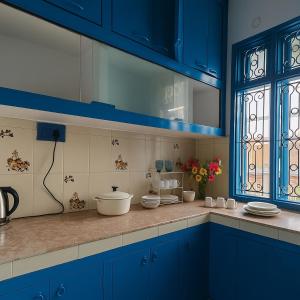 a blue kitchen with blue cabinets and a sink at Kashivas - 2BHK near Assi Ghat in Varanasi