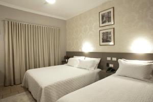 a hotel room with two beds with white sheets at Nohotel Nova Odessa in Nova Odessa