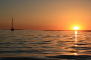 un tramonto su un corpo d'acqua con una barca a vela di Apartamentos BeSlow La Antilla a La Antilla