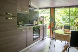 a kitchen with wooden cabinets and a table and a dining room at Corgi-Flowerhuisje in Lanaken