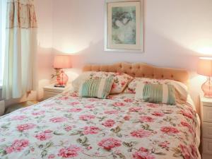 a bed with pink flowers on it with two pillows at Berllys - Uk48482 in Criccieth