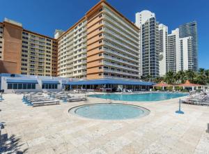 a hotel with a pool and chairs and buildings at Pet Friendly Studio Beach and Pool Access, gym ! in Sunny Isles Beach