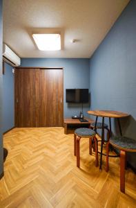 a room with a table and chairs and a television at Rokuhara Inn in Kyoto
