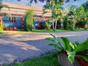 a building with palm trees in front of a street at Pilton Resort in Ban Huai Yang