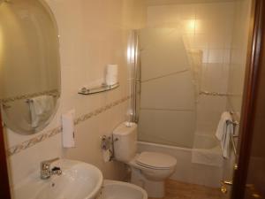 Un baño con inodoro, lavabo y ducha. en Hotel San Jorge, en Alcalá de los Gazules