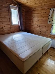 a bed in a room with wooden walls and a window at Paljarinne in Hulmi