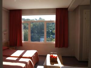 1 dormitorio con 2 camas y una ventana con cortinas rojas en Hotel San Jorge, en Alcalá de los Gazules