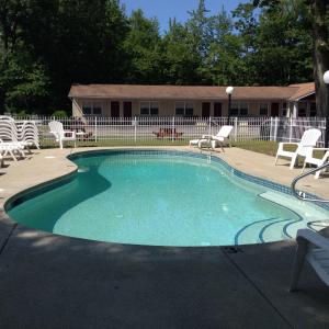 a small swimming pool with chairs and a house at Marcotte Motor Court in Old Orchard Beach