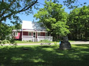 a red and white house with a picnic table in the grass at Maison Du Vieux Chemin in Saint-Philémon