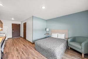 a bedroom with a bed and a blue chair at WoodSpring Suites Jackson I-40 in Jackson +36 photos