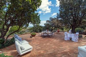 un patio avec des chaises blanches, des tables et des arbres dans l'établissement Suite cucinino, bagno, ingresso indipendente in" Villa VìVì", à Siniscola