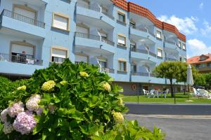 ein blaues Gebäude mit Blumen davor in der Unterkunft Apartamentos Montalvo Playa in Montalvo