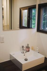 Un lavabo blanco en un baño con espejo. en Sugi Crossroads, en Myoko