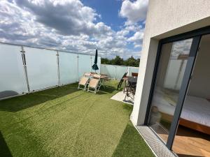 Un balcón con césped verde y una cama y una mesa. en Le 147 Parc Entre Paris et Disney, en Champigny-sur-Marne