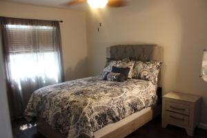 een slaapkamer met een bed met een dekbed en een raam bij Luxurious 5-Bedroom Retreat with Saltwater Pool and Spa in Elk Grove +32 foto's