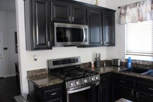 een keuken met zwarte kasten, een fornuis en een magnetron bij Luxurious 5-Bedroom Retreat with Saltwater Pool and Spa in Elk Grove