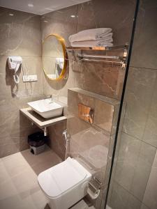 a bathroom with a toilet and a sink and a mirror at Hotel Alfa Suites in Mumbai