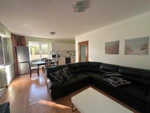 a living room with a black couch and a kitchen at Apartment Sunny Seasons Byala in Byala