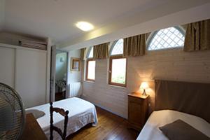 a bedroom with two beds and a table with a lamp at Les appartements du Relais du Jacquet in Navarrenx