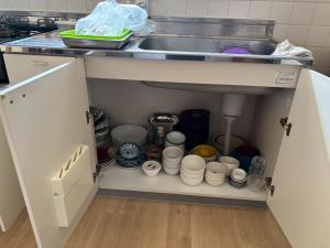 a kitchen cabinet filled with dishes and a sink at ゆいくる処まーす in Motobu
