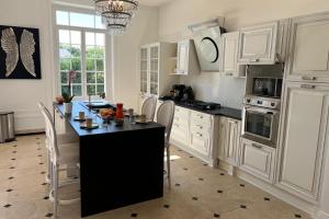 een keuken met witte kasten en een zwart eiland met stoelen bij Hôtel Particulier - 5 minutes de Reims in Reims