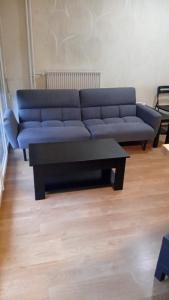 Appart cosy proche de Paris في فيلوجويف: غرفة معيشة مع أريكة زرقاء وطاولة قهوة