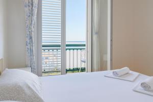a bedroom with a white bed and a large window at Apartments Nikola in Gradac