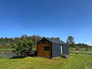 a tiny house on the side of a lake at Mēness Namiņš in Vidriži