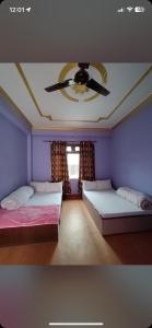 a bedroom with two beds and a ceiling fan at Sunita Hotel And Lodge in Rāmechhāp