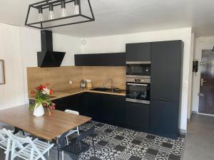 cocina con armarios negros y mesa de madera en Appartement St Cast centre ville 50 m de la plage, en Saint-Cast-le-Guildo
