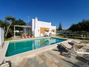a swimming pool with two chairs and a house at Olas de Conil in Conil de la Frontera