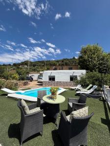 a patio with chairs and a table and a pool at Casa rural Los Rosales in Lanjarón