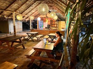 a woman sitting at a picnic table with a laptop at Pearl Inn Green in Nilaveli