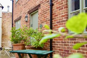 a green picnic table in front of a brick building at Templar Mews, town centre 2 bedroom, 2 bathroom house in Cirencester