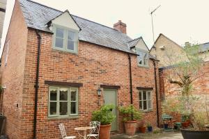 a brick house with chairs and tables in front of it at Templar Mews, town centre 2 bedroom, 2 bathroom house in Cirencester