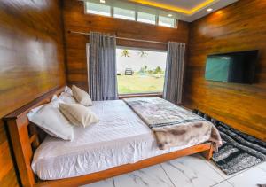 une chambre avec un lit avec une fenêtre et une télévision dans l'établissement JC Den Private Villas Kochi by VOYE HOMES, à Cochin