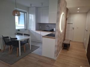 a kitchen with white cabinets and a table and chairs at Tauzen Apartaments 31 in Katowice