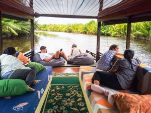 a group of people sitting on a boat on a river at Orangutan Borneo Tour Tanjung Puting in Pangkalan Bun