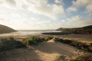 a sandy beach with a view of the ocean at Milton Cottage Manorbier in Manorbier