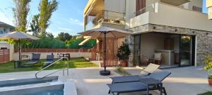 a patio with chairs and an umbrella and a pool at Sagini Suites in Paradisos